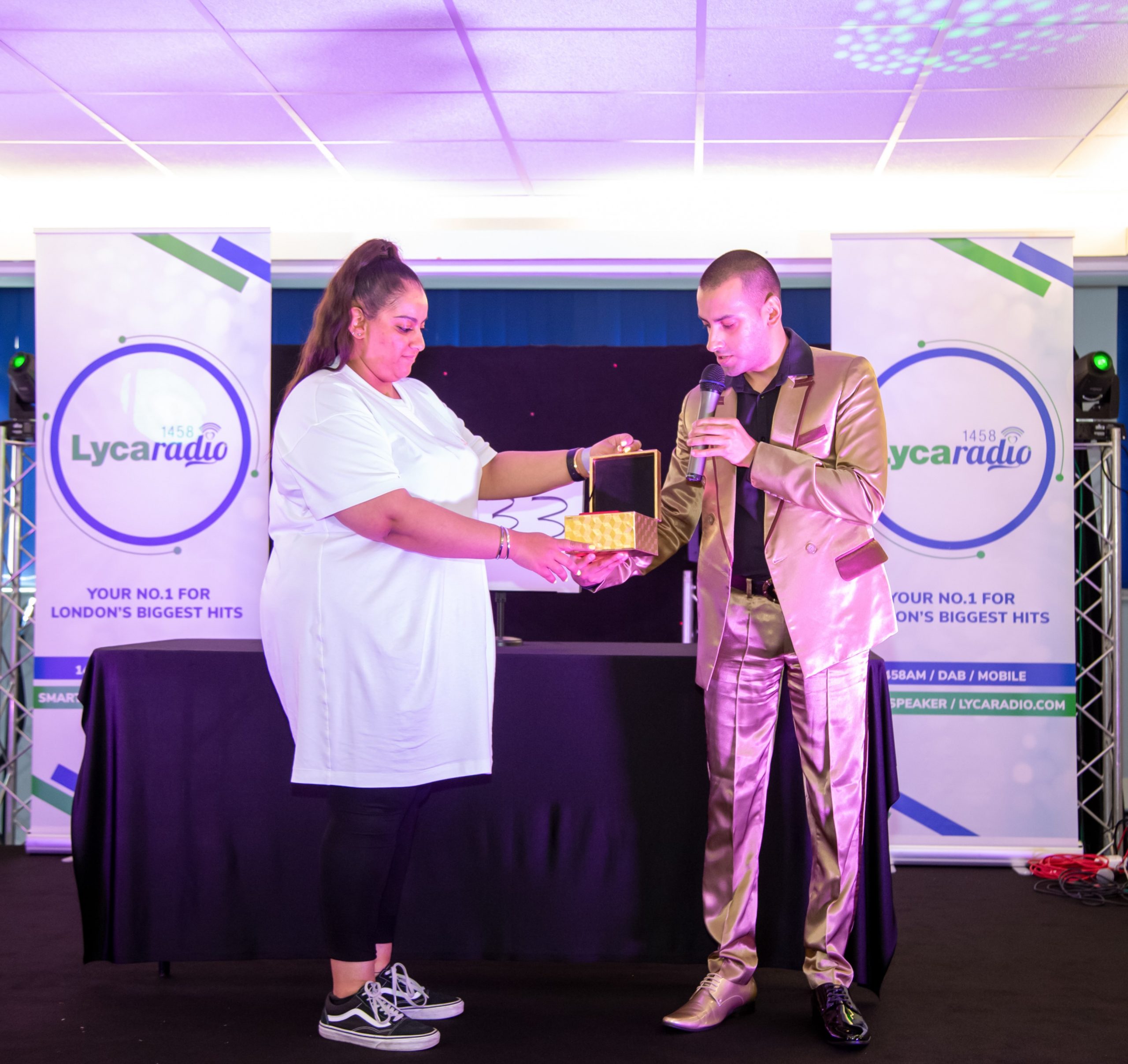 Wearing a stylish silk gold suit whilst performing on stage. What's in the gift box?!