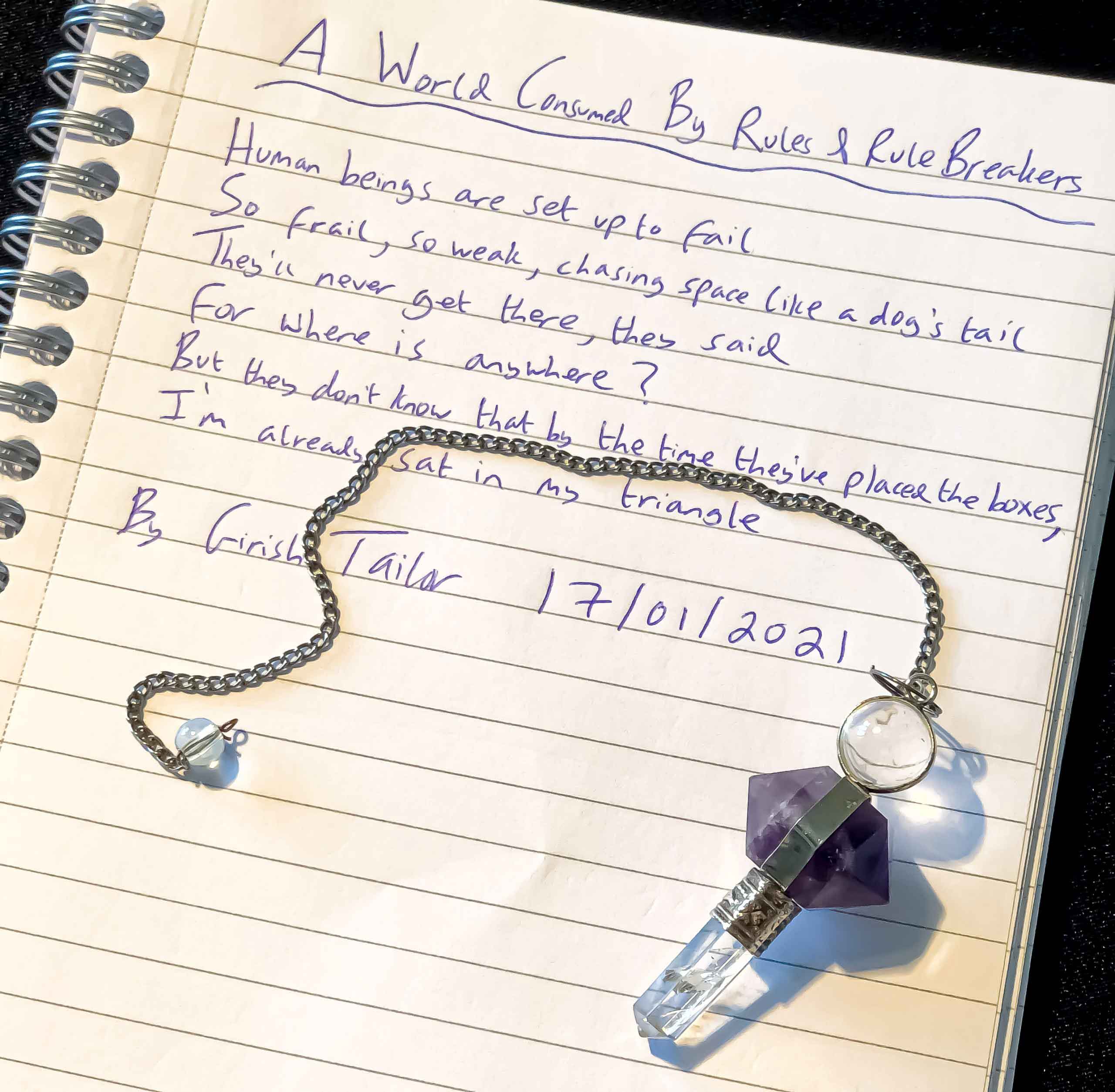 A poem Girish wrote about social conditioning and stepping outside of boxes. Also shown is a purple pendulum of Girish’s