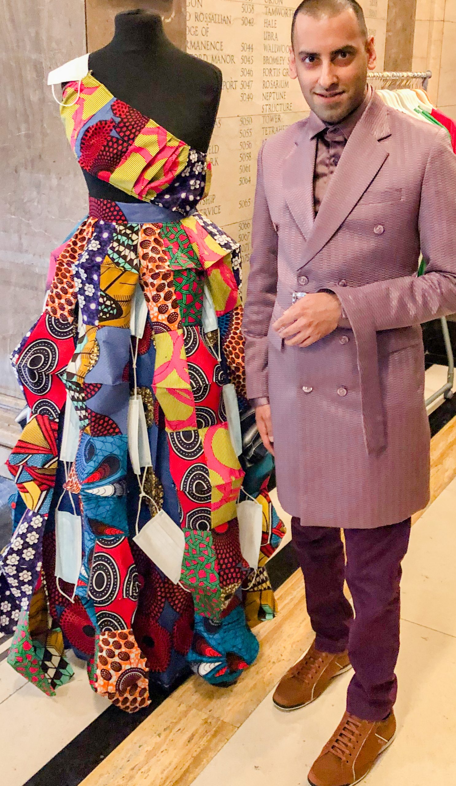 Dressed in purple at Africa Fashion Week London (AWFL), next to an outfit made entirely out of face masks - the Divoc-Divoc outfit by African Caribbean Emporium