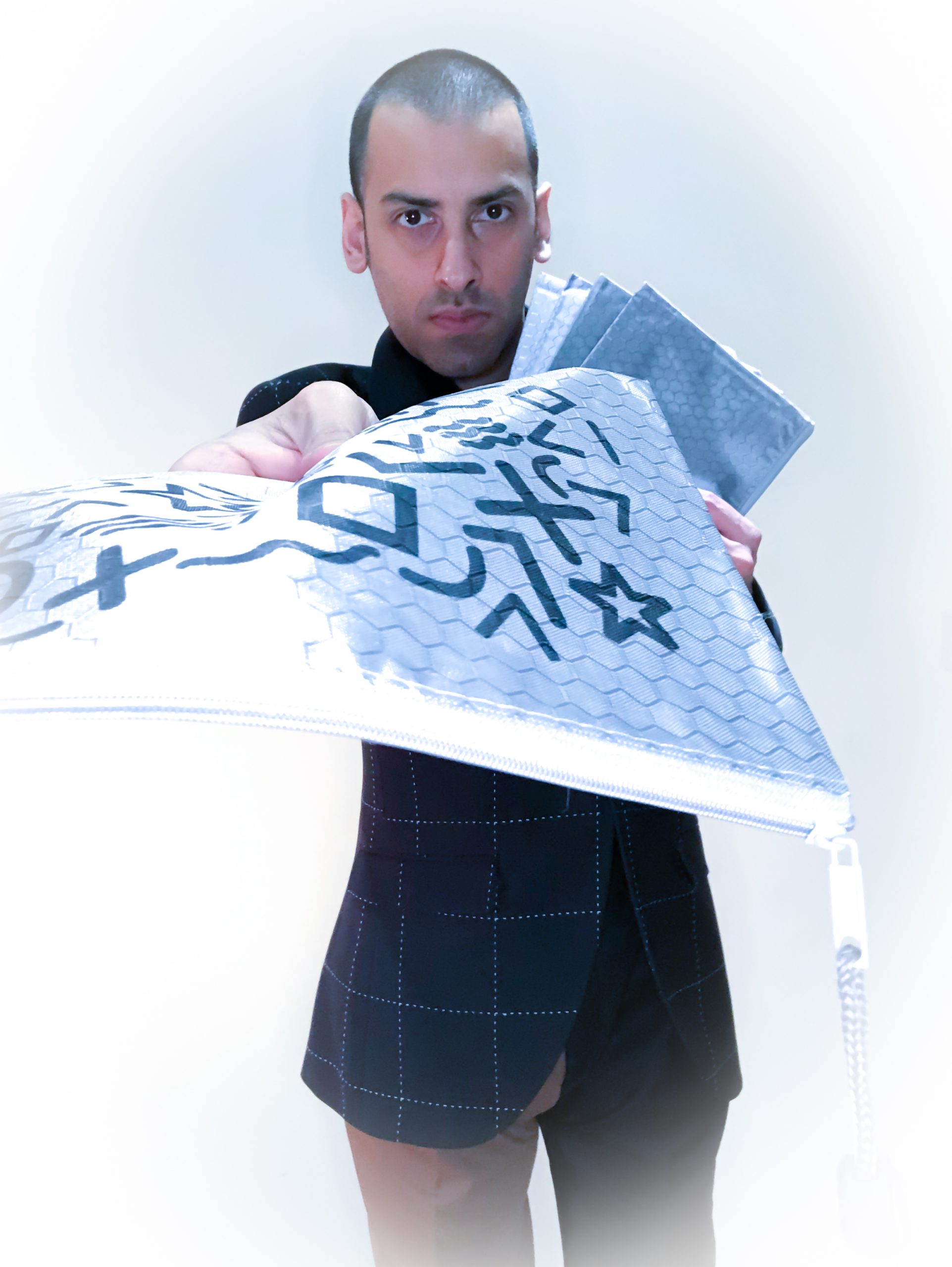 Offering a stylish fashion bag or folder with shapes and patterns as the design, dressed in spliced trousers and a black blazer