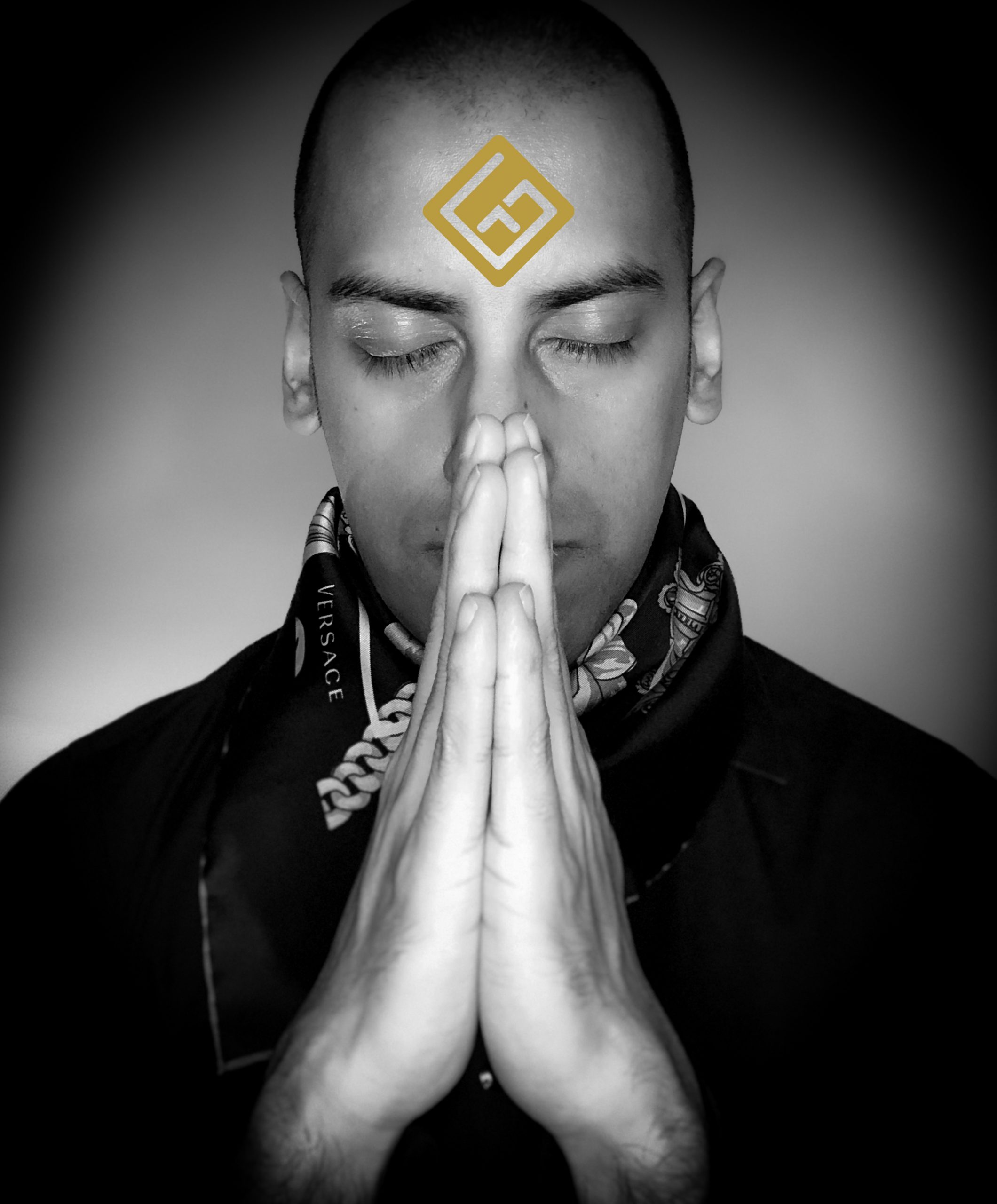 Classy and stylish black and white fashion photo showing Girish Tailor – The International Indian Mind Reader, in a prayer position with his logo on his forehead like a Hindu tilak or chandlo, dressed elegantly in a Versace foulard
